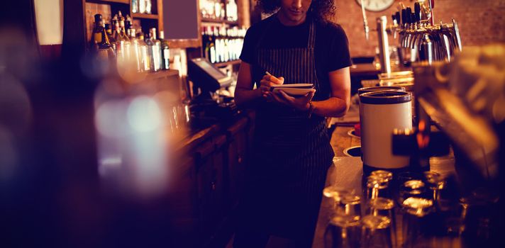 Young waiter writing on diary in pub