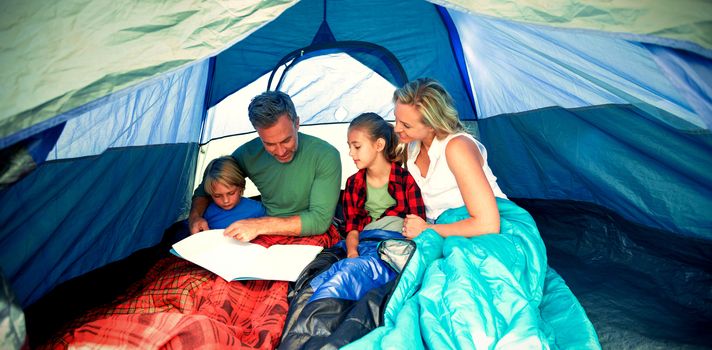 Family reading book together in the tent