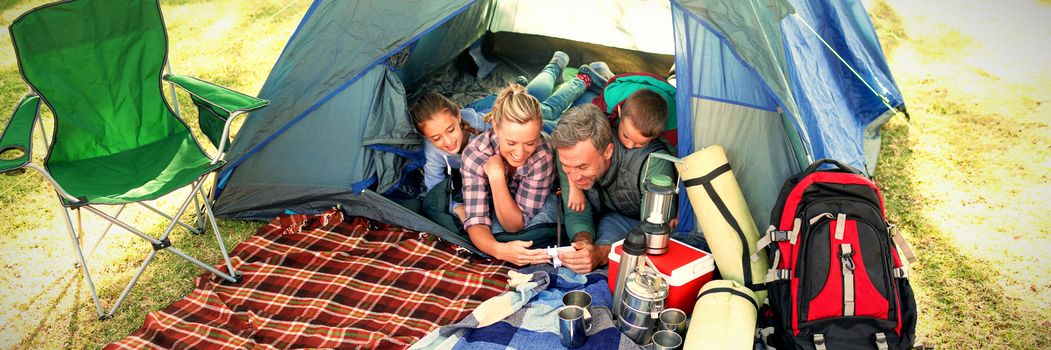 Family looking at camera in the tent at campsite