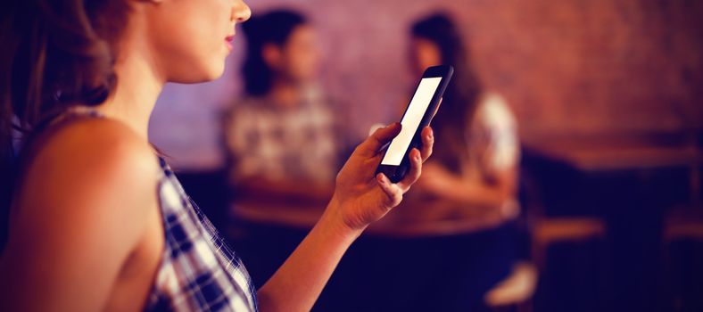 Young woman using mobile phone in pub