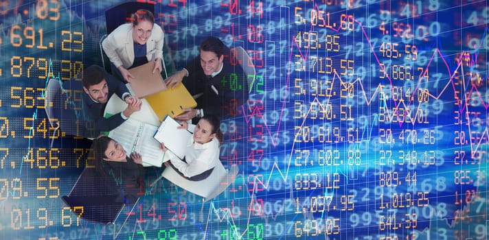 High angle portrait of business people sitting at table against stocks and shares
