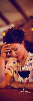 Upset woman sitting with hands on forehead in pub