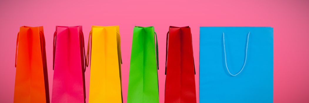 Shopping bags against plain pink background