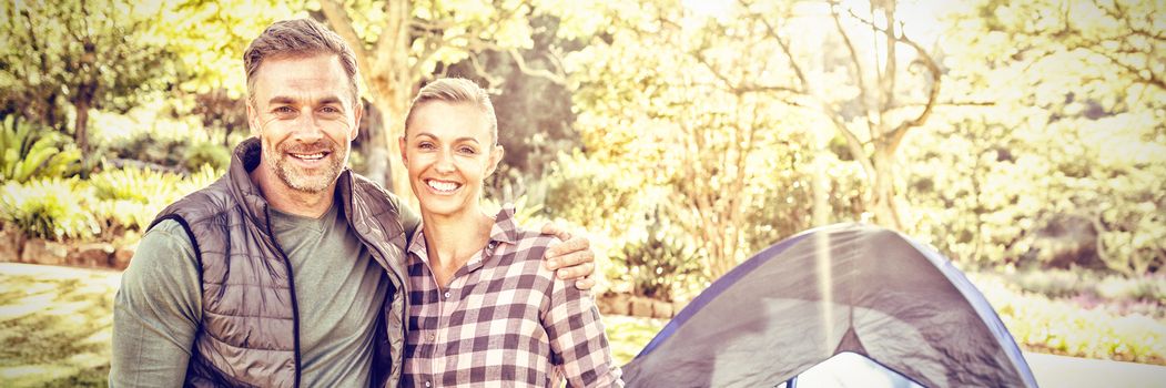 Couple smiling at camera while kids sitting in tent at campsite