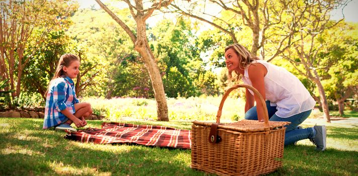 Mother and daughter spreading the picnic blanket in park