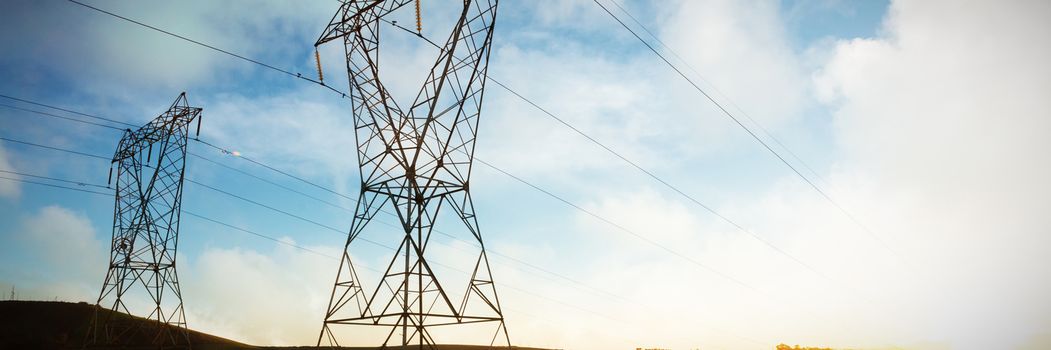 Blue sky with white clouds against the evening electricity pylon silhouette