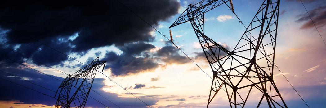 Blue and orange sky with clouds against the evening electricity pylon silhouette