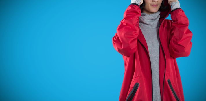 Woman in hooded jacket standing against white background against blue background