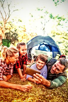 Smiling family taking a selfie outside the tent