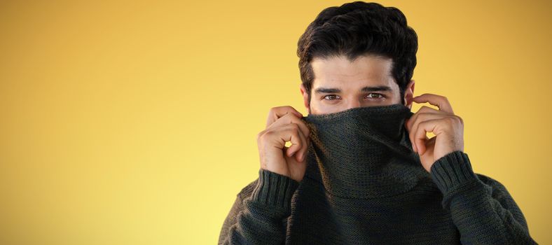 Portrait of man hiding face with sweater against abstract yellow background