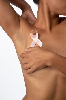 Shirtless woman for breast cancer awareness with ribbon on white background
