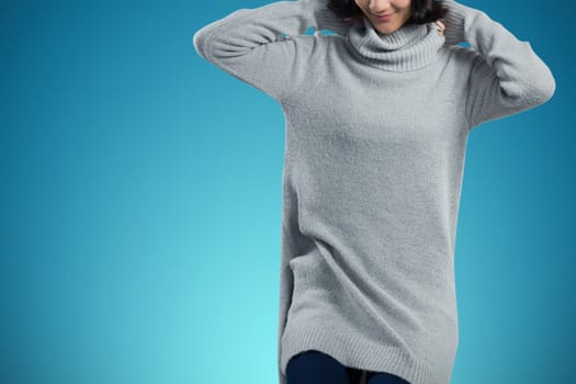 Woman in winter clothing posing against white background against abstract blue background