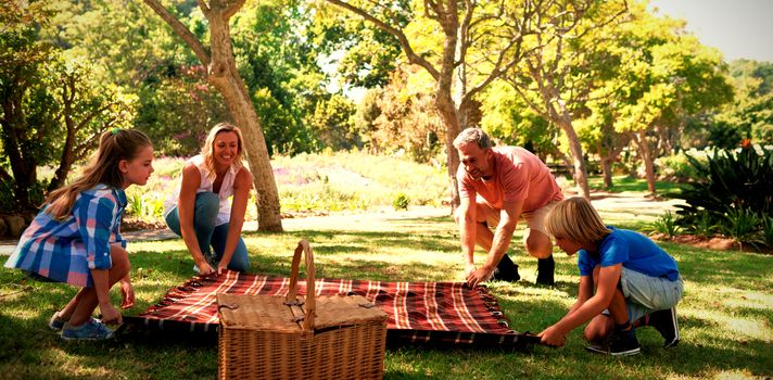 Family spreading the picnic blanket in park