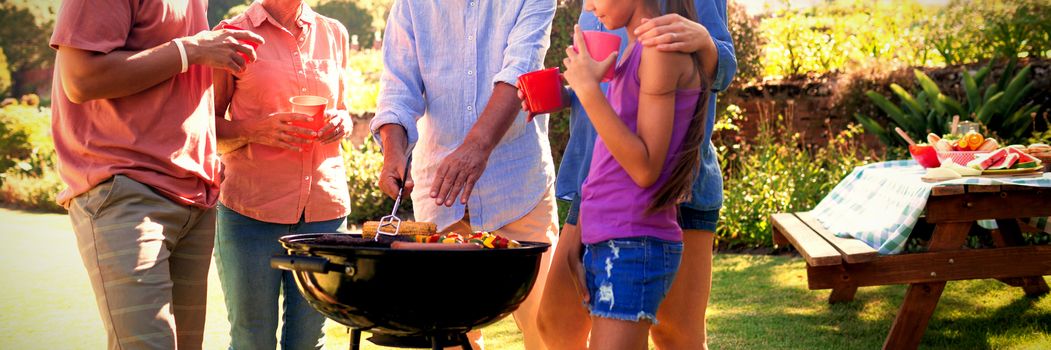 Family talking while preparing barbecue in the park on a sunny day