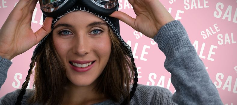 Portrait of woman with ski goggles against pink background