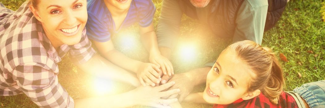 Portrait of happy family lying and putting their hands together in park