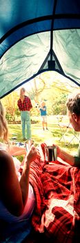 Rear view of couple having coffee and looking at kids playing outside the tent