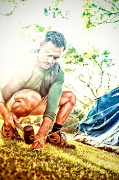 Man setting up the tent at campsite on a sunny day