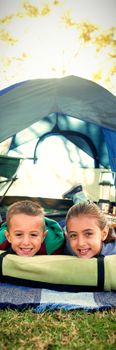 Portrait of smiling siblings lying outside the tent