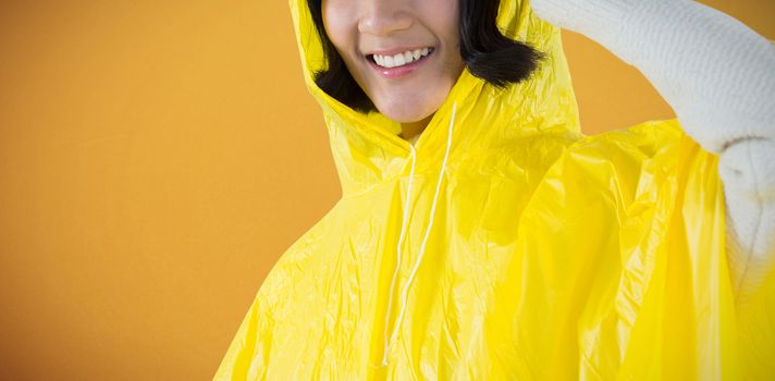 Woman wearing yellow raincoat against white background against orange background