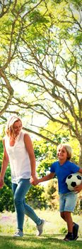 Mother and son walking in the park with football on a sunny day