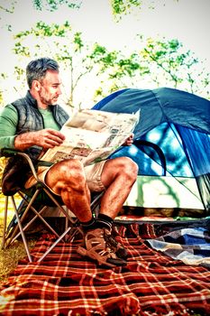 Man reading the map outside the tent at campsite