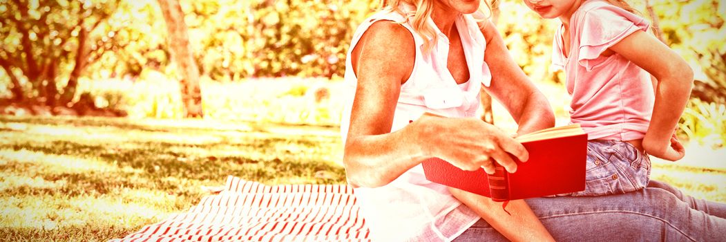 Mother and daughter reading novel in park on a sunny day