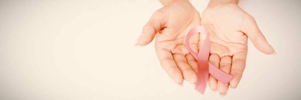 Two hands showing pink ribbon against breast cancer against white background
