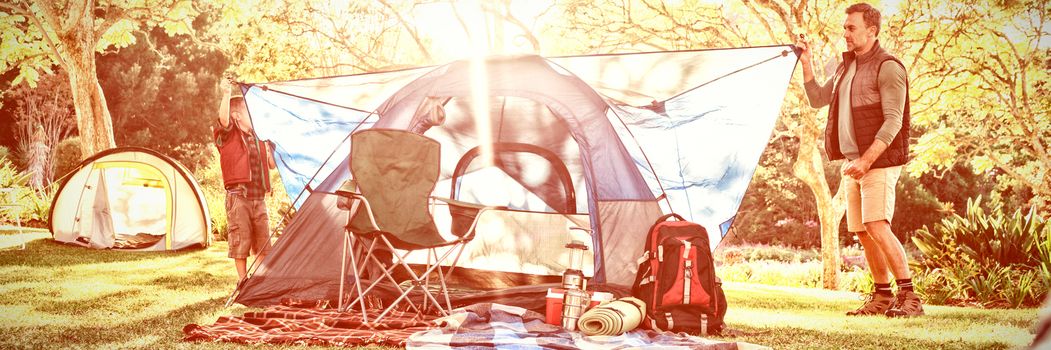 Father and son setting up a tent at campsite