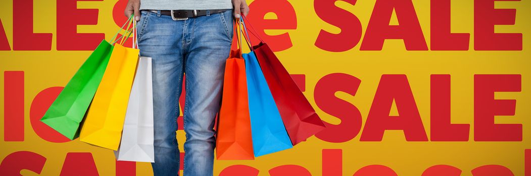 Low section of man carrying colorful shopping bag against abstract mustard background