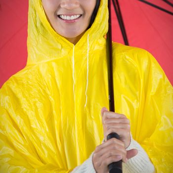 Woman in yellow raincoat holding an umbrella against white background with vignette