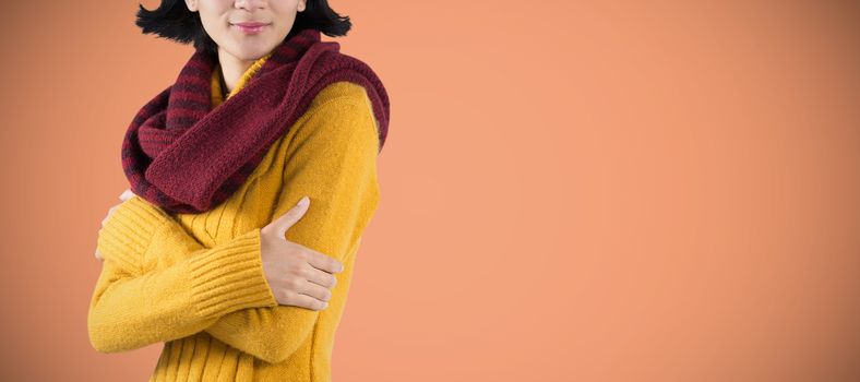 Woman in winter clothing posing against white background against orange background 