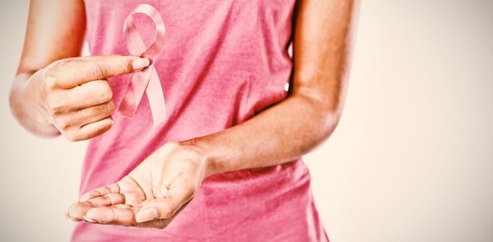 Woman holding pink ribbon between fingers for breast cancer awareness