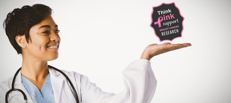 Breast cancer awareness message against smiling female doctor shows a copy space with her hand