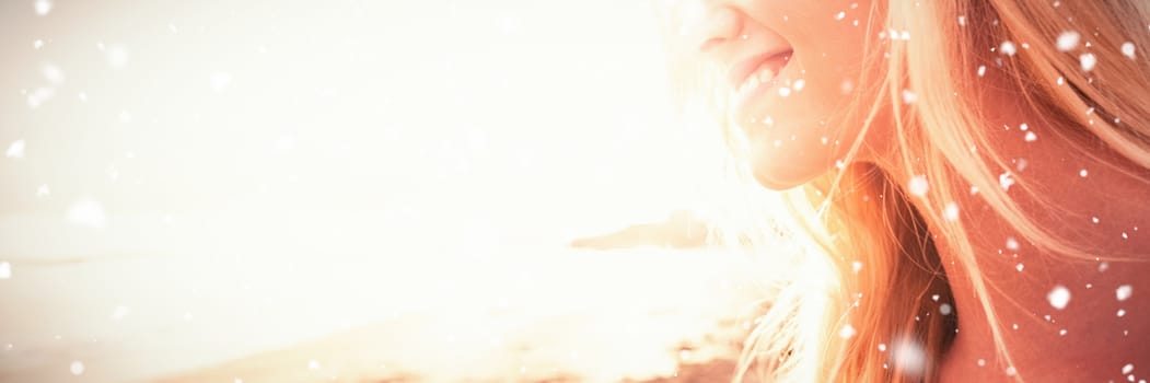 Snow falling against smiling woman looking away at beach