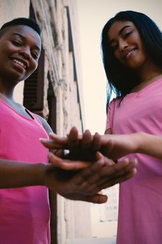 Portrait of women wearing pink for breast cancer and putting hands together in park