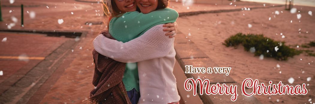 Christmas card against female friends hugging each other
