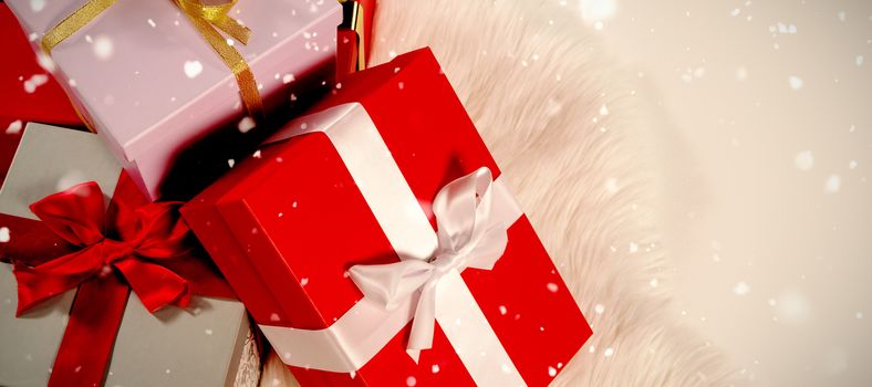 Snow falling against christmas gifts on a white fur
