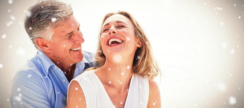 Happy couple laughing together against snow falling