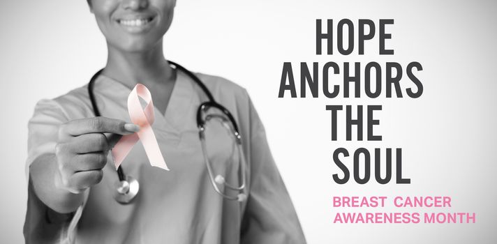 Breast cancer awareness message against smiling nurse holding breast cancer awareness pink ribbon between her fingers