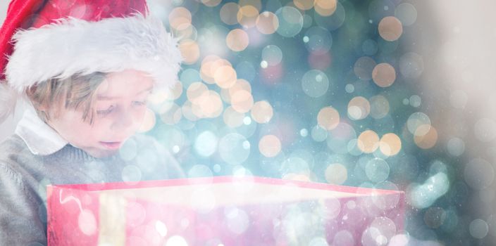 Child opening his christmas present against blue abstract light spot design