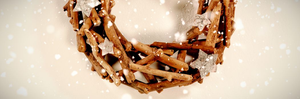 Snow falling against small christmas crown made of sticks