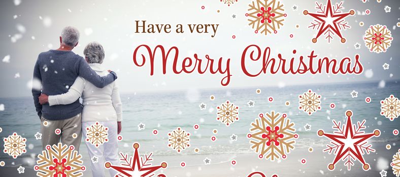 Christmas card against rear view of senior couple embracing at beach
