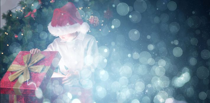 Child opening his christmas present against blue abstract light spot design