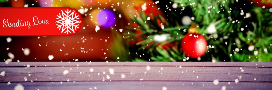 Banner sending love against multi colored bauble decorations on christmas tree