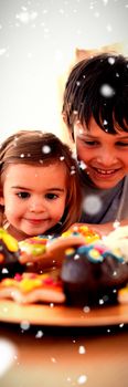 Brother and sister looking at confectionery against snow falling