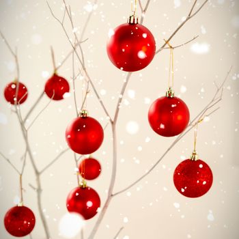 Snow falling against red christmas balls on branches frame
