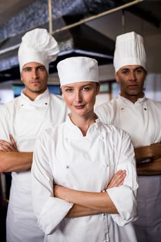 Group of chefs standing with arms crossed in kitchen at hotel