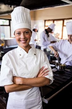 Female chef standing with arms crossed in kitchen at hotel