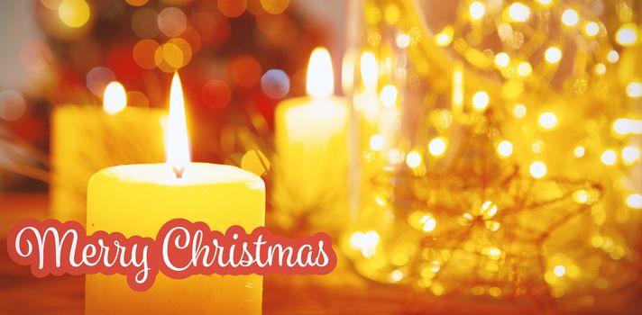 White and red greeting card against christmas candles on wooden table